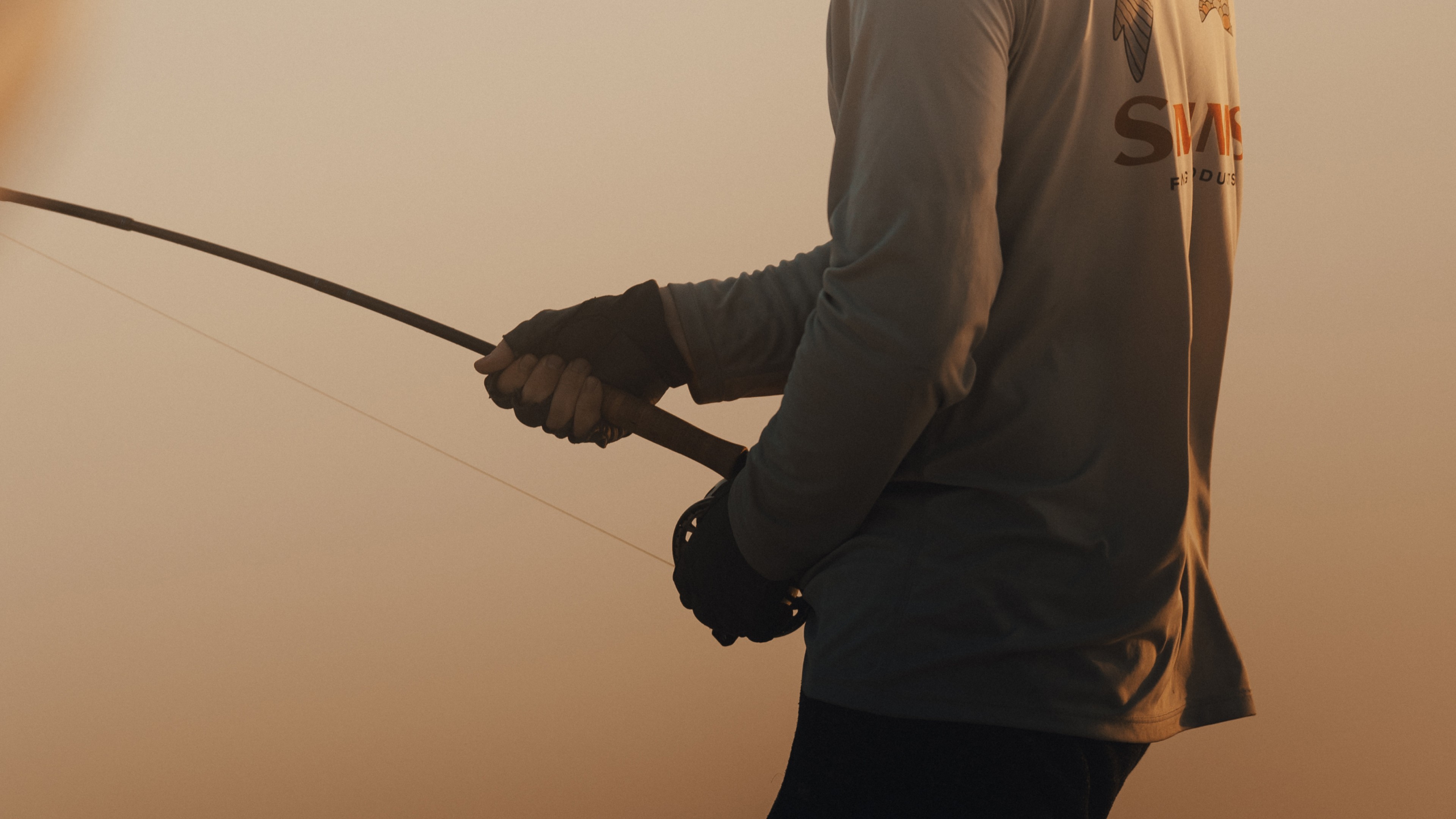 Angler holding a bent fly fishing rod during golder hour
