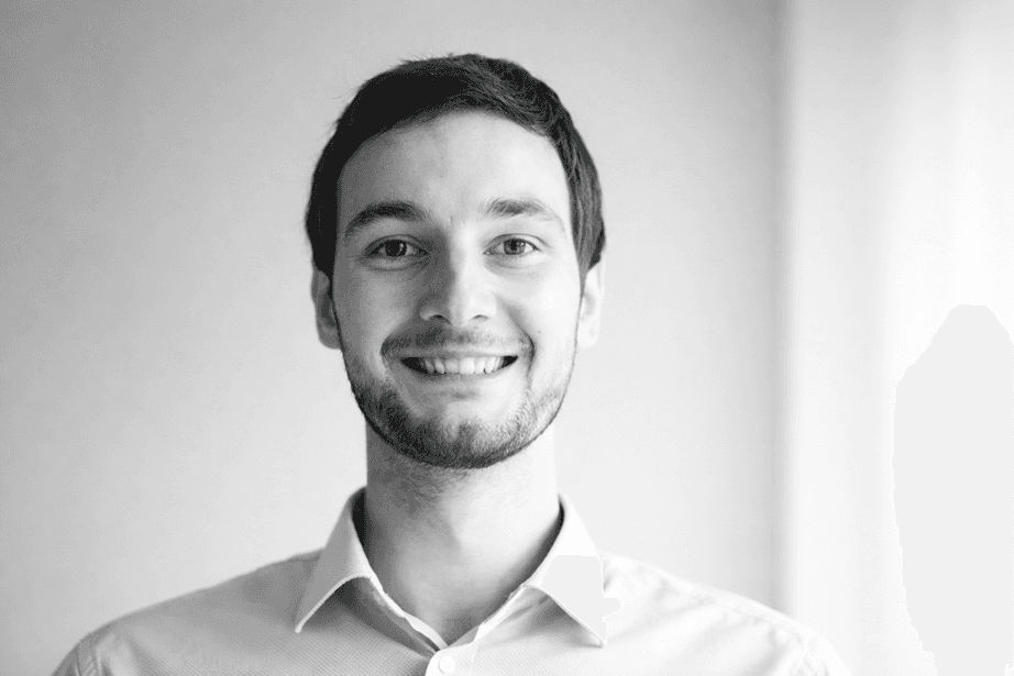 Portrait of a smiling young man with a beard in black and white.