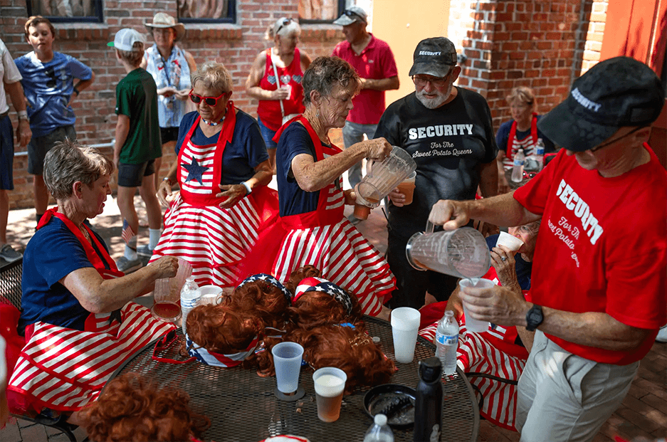 Women in red, white and blue dresses and men in T-shirts that say “Security” pour drinks for one another.