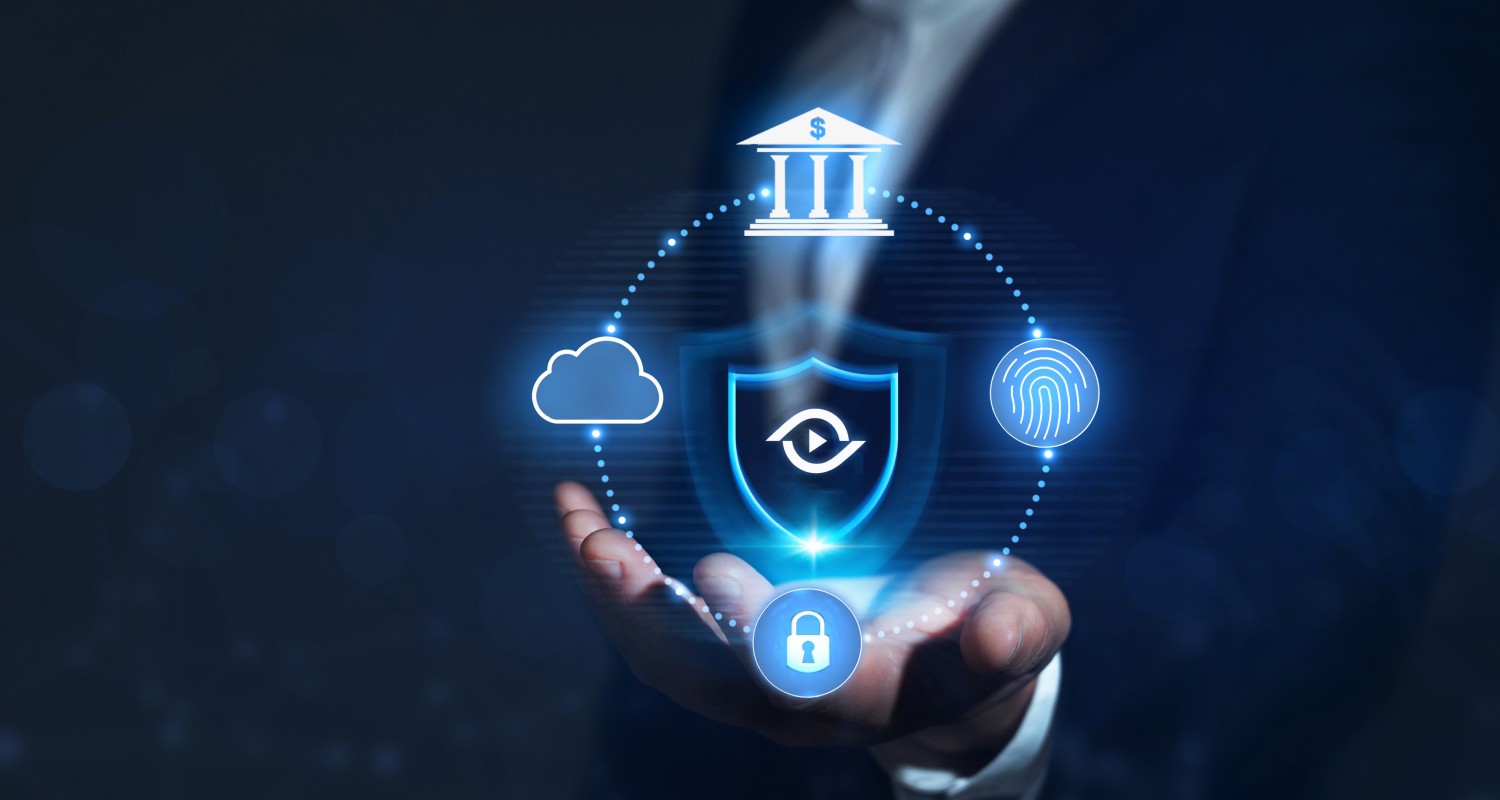A business professional holds out a hand displaying a glowing digital shield icon surrounded by symbols representing banking, cloud storage, biometrics, and cybersecurity, illustrating financial crime prevention and anti-smurfing protection technology.