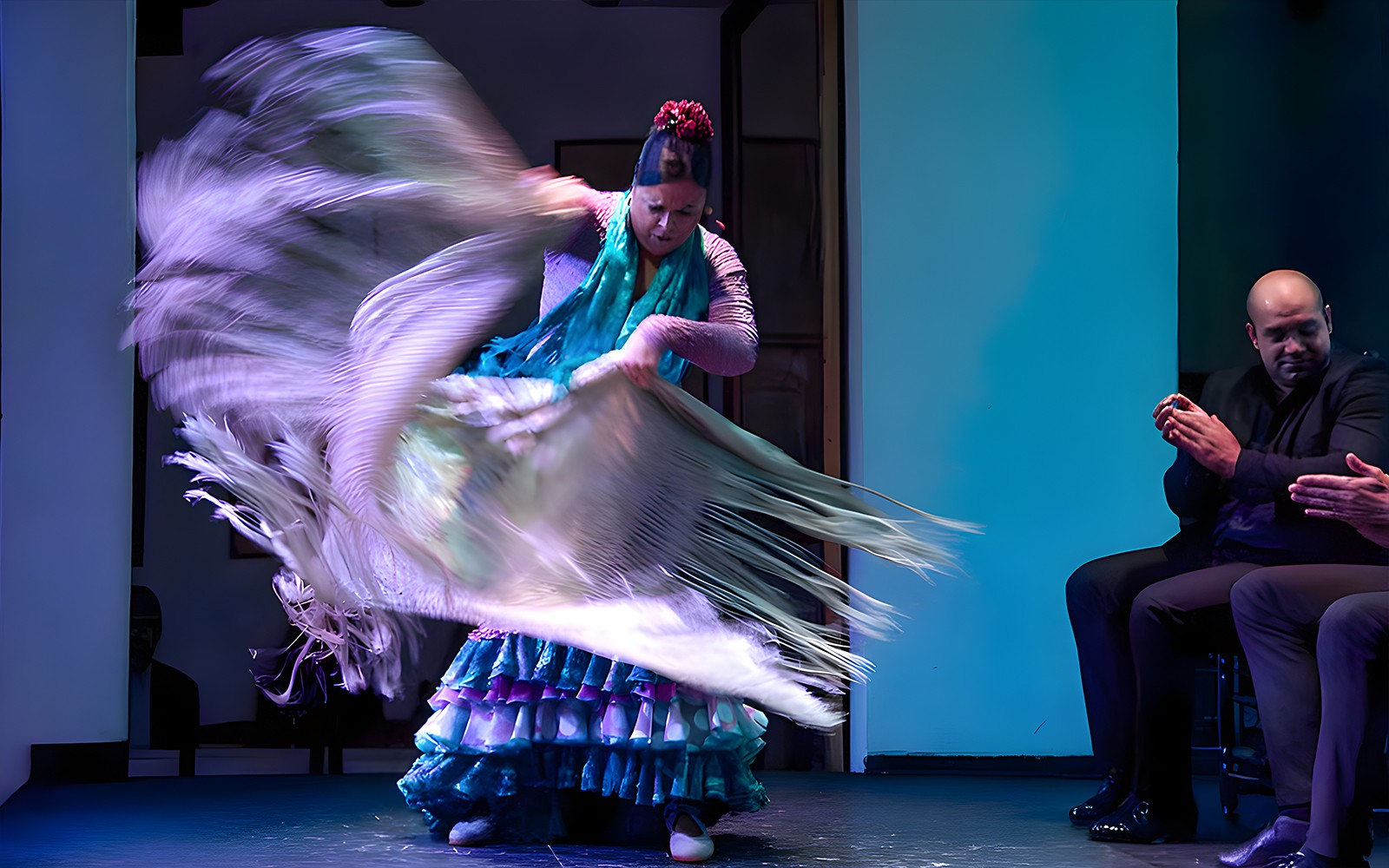 Flamenco dancer performing at Tablao El Arenal with musicians clapping.
