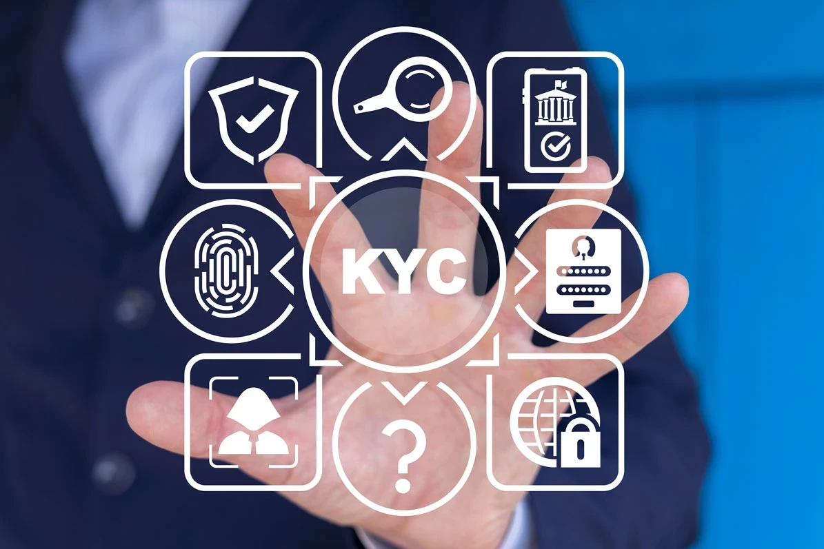 A person walks in front of large stone arches with dark doors, flanked by tall columns, in a historic building.