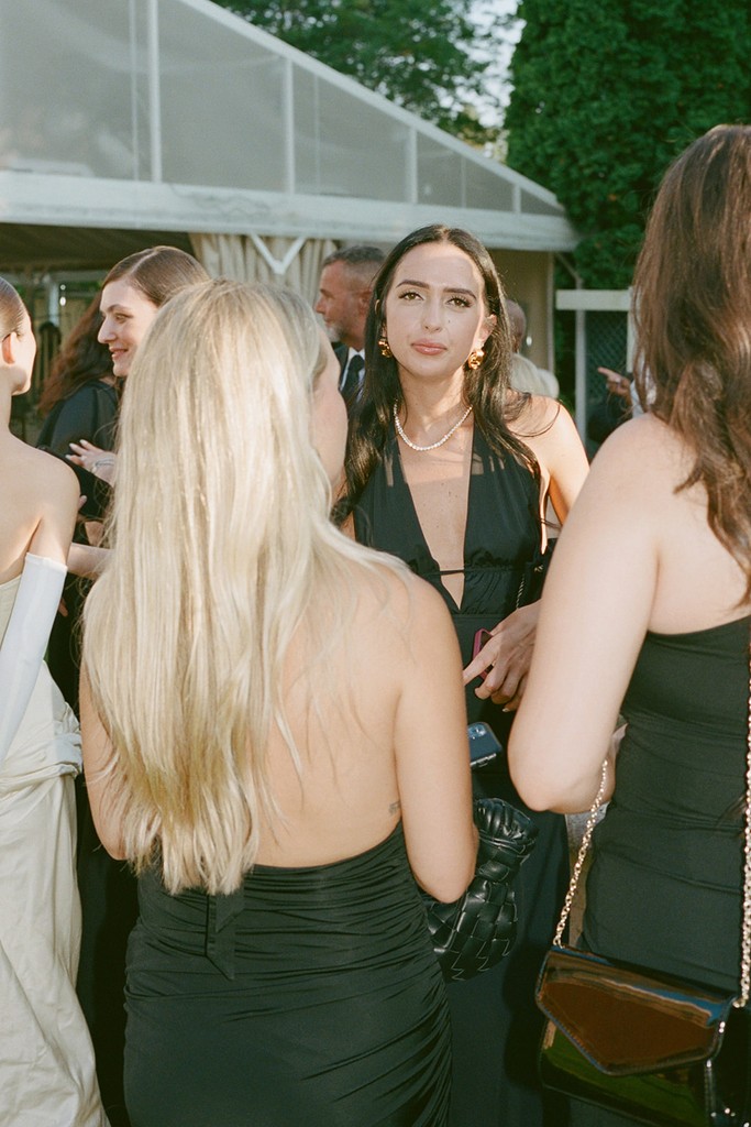 Wedding guests in black evening attire socialising outdoors during a summer wedding reception
