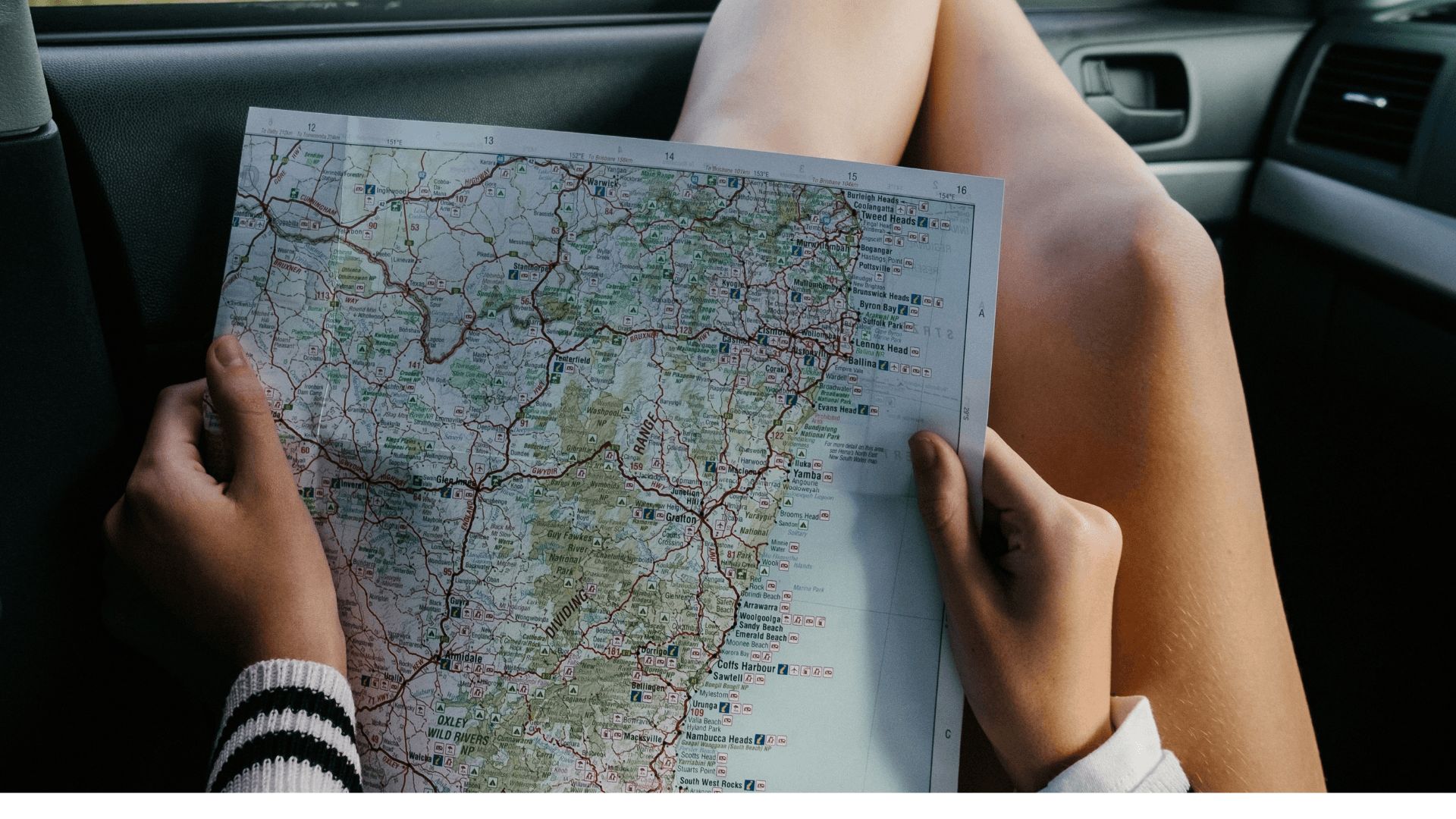Someone sitting in a car looking at a paper roadmap
