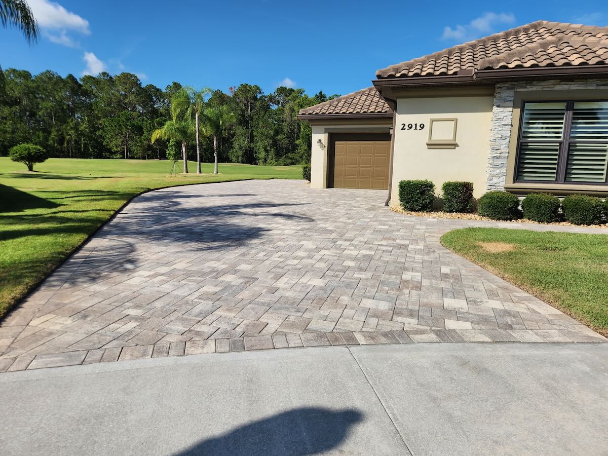 Before paver sealing - faded driveway with weeds in Port Orange FL