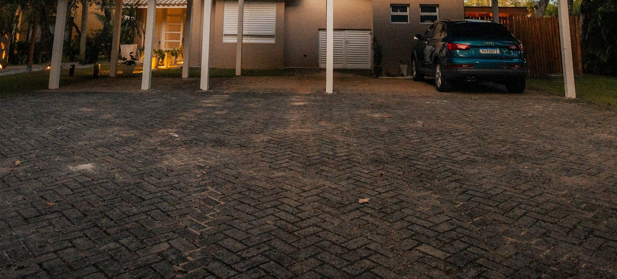 Jardin potager avec rangées de légumes et serre en arrière-plan.