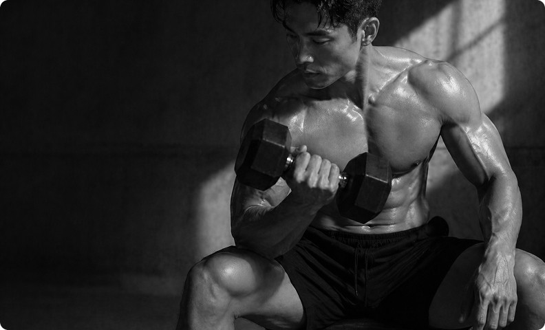 Muscular man curling a dumbbell during an intense workout