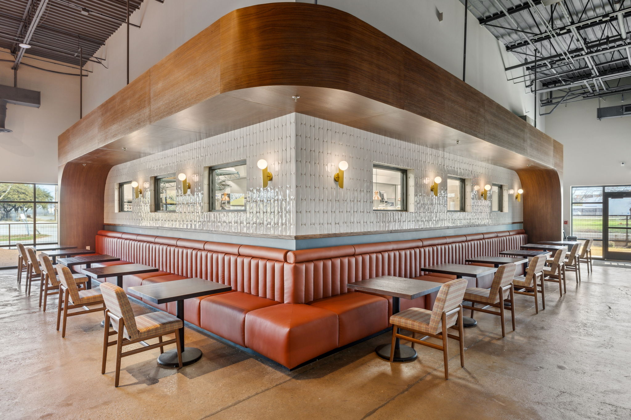Seating area inside At Fault pickleball venue in Dallas, featuring wraparound banquette seating, tiled walls, and the bar structure integrated into the interior layout.