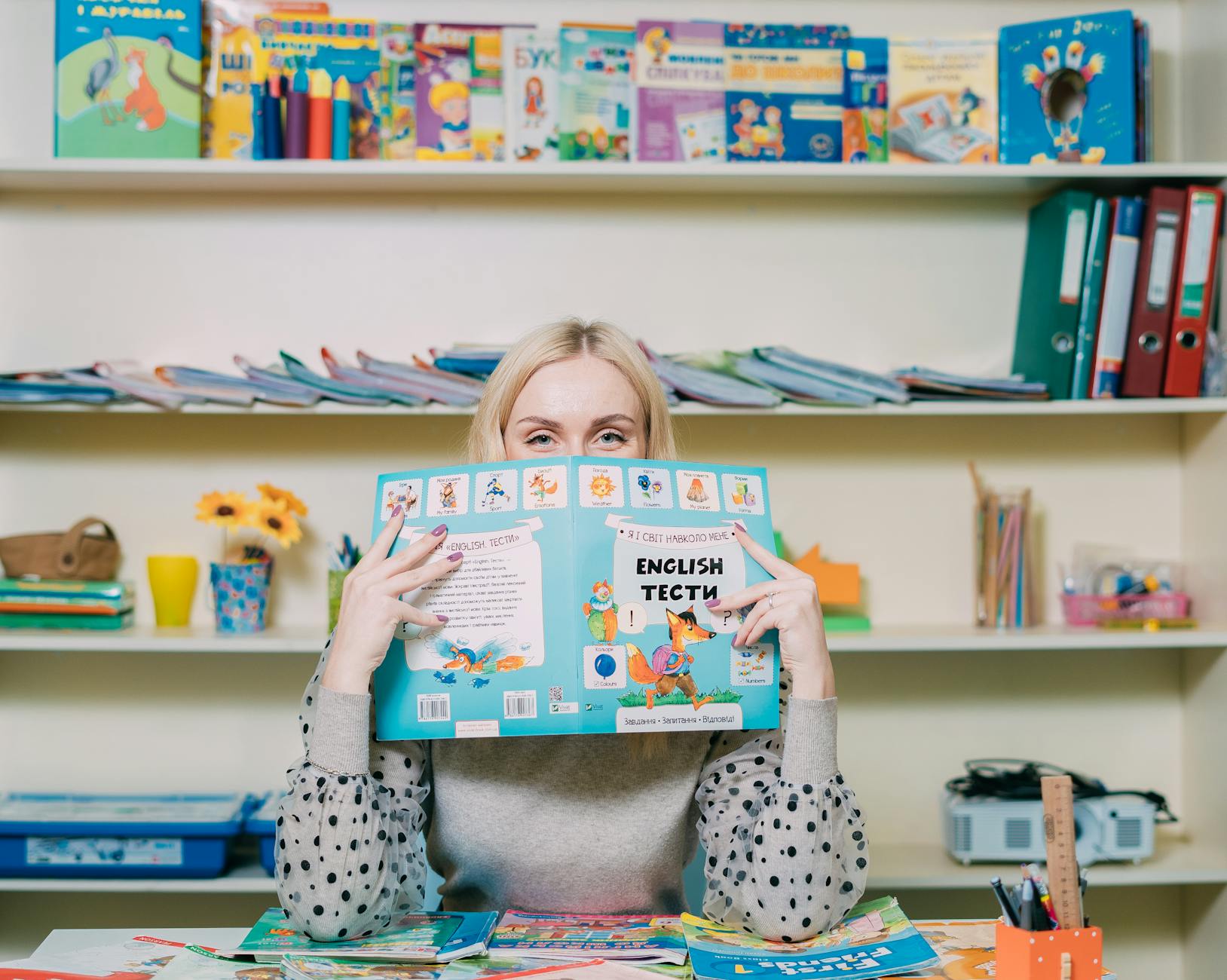 Close-up of a teacher's hands highlighting a standards-aligned lesson plan next to a stack of textbooks.