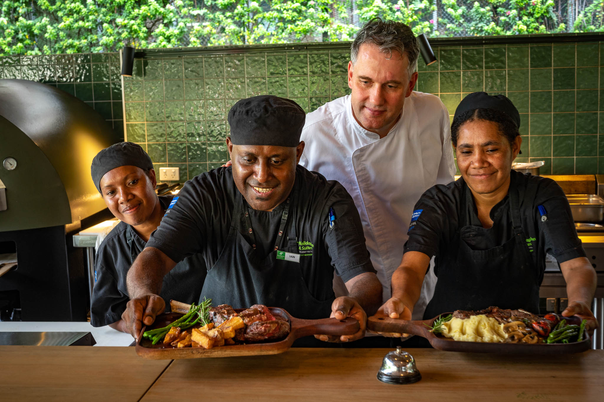 FAYA HAUS chefs preparing a dish with a variety of meats and vegetables, sharing a moment with restaurant staff