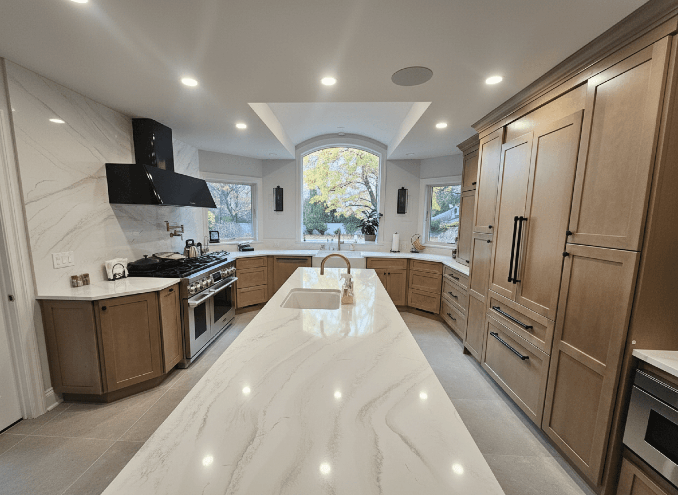 Kitchen renovation with large quartz island, custom cabinetry, and modern appliances