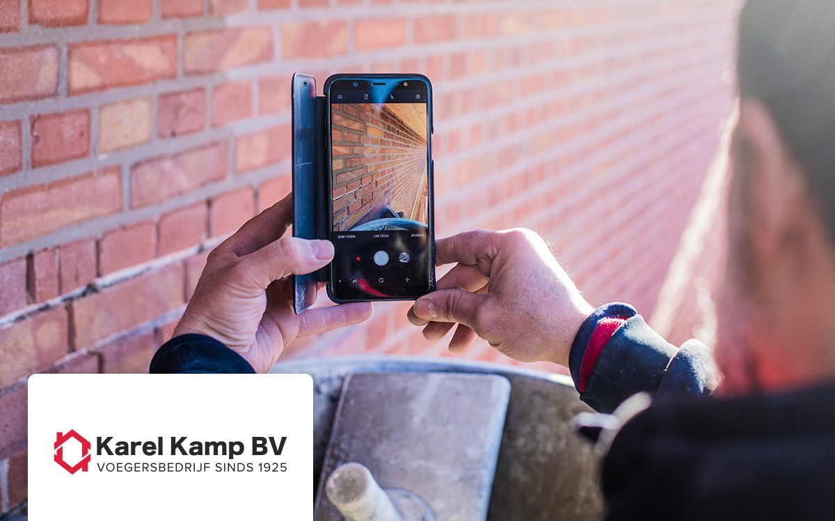 Een medewerker fotografeert metselwerk met een telefoon, uit de oorspronkelijke klantcase van Karel Kamp BV.