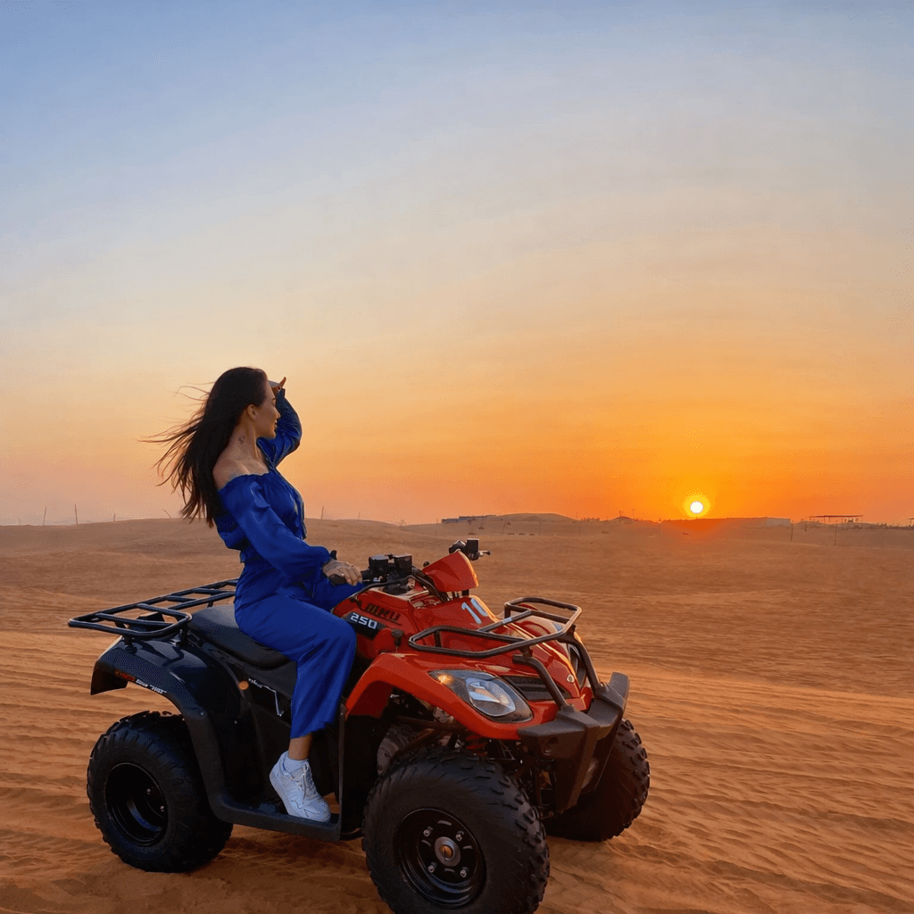 Woman riding an ATV during a sunset desert safari in Lahbab dunes Dubai with Dune Quest Tours