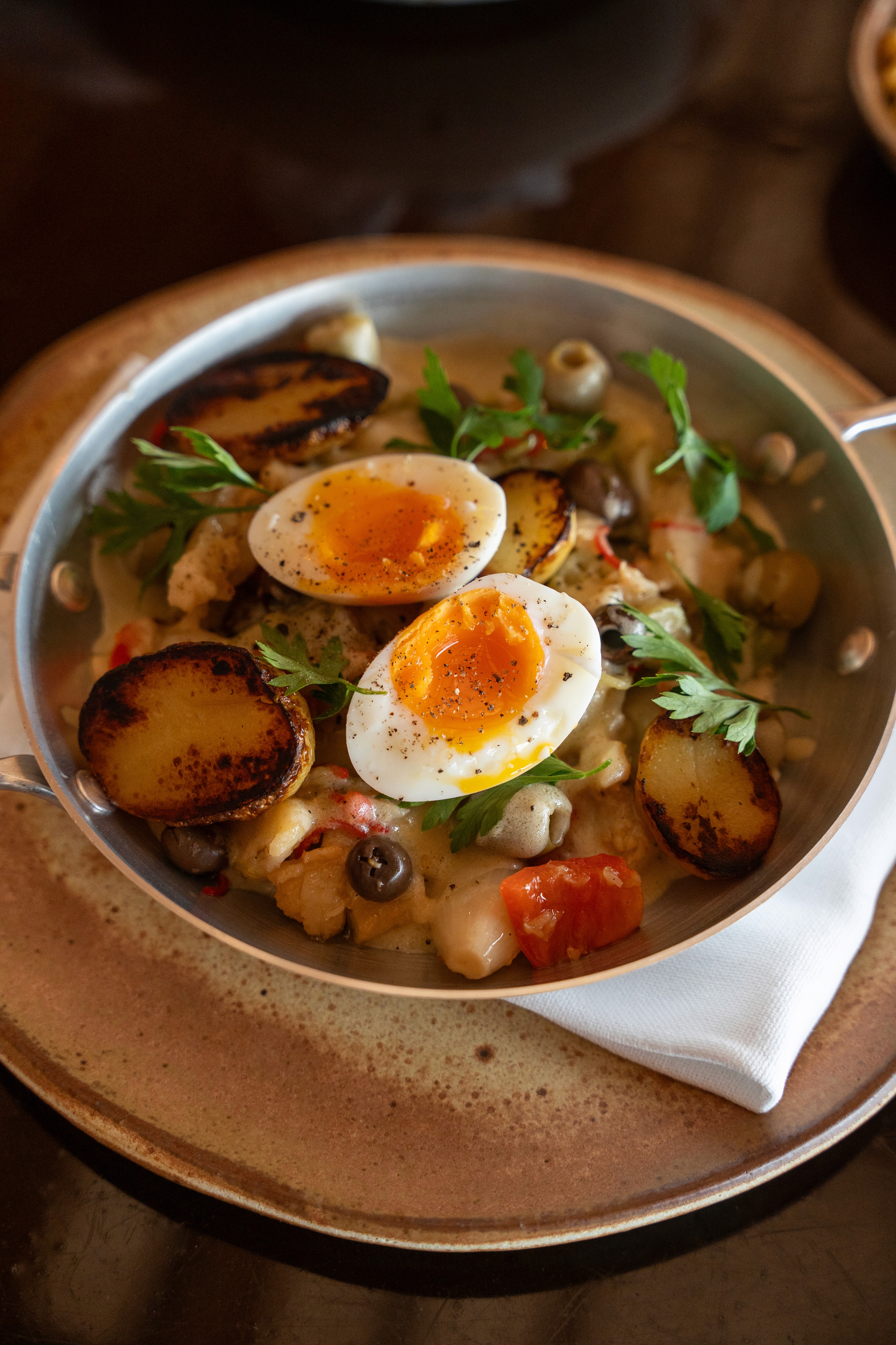 Grand stone building with glowing windows under a deep blue twilight. Dramatic lighting casts a mysterious, elegant ambiance. Surrounded by shadowy trees.