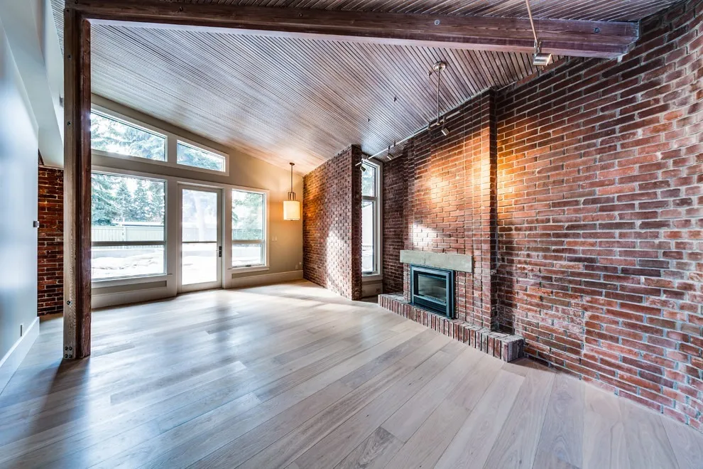 Image of "KHD Homes interior design showcasing exposed brick, wooden beams, and vaulted ceiling in a spacious room."