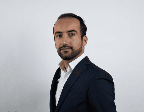 Foto van Niwar, eigenaar van vsocheque.nl. Man in pak die de camera in kijkt.