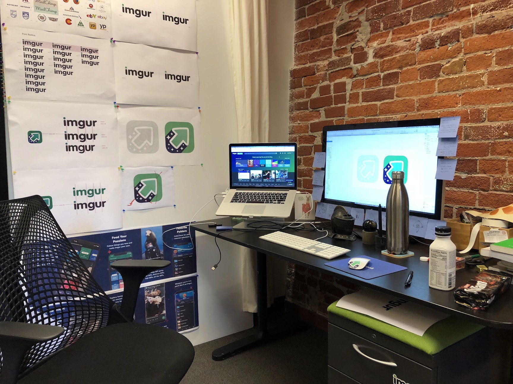 Modern home office setup with a monitor, ergonomic chair, keyboard, and indoor plants near a window with blinds.