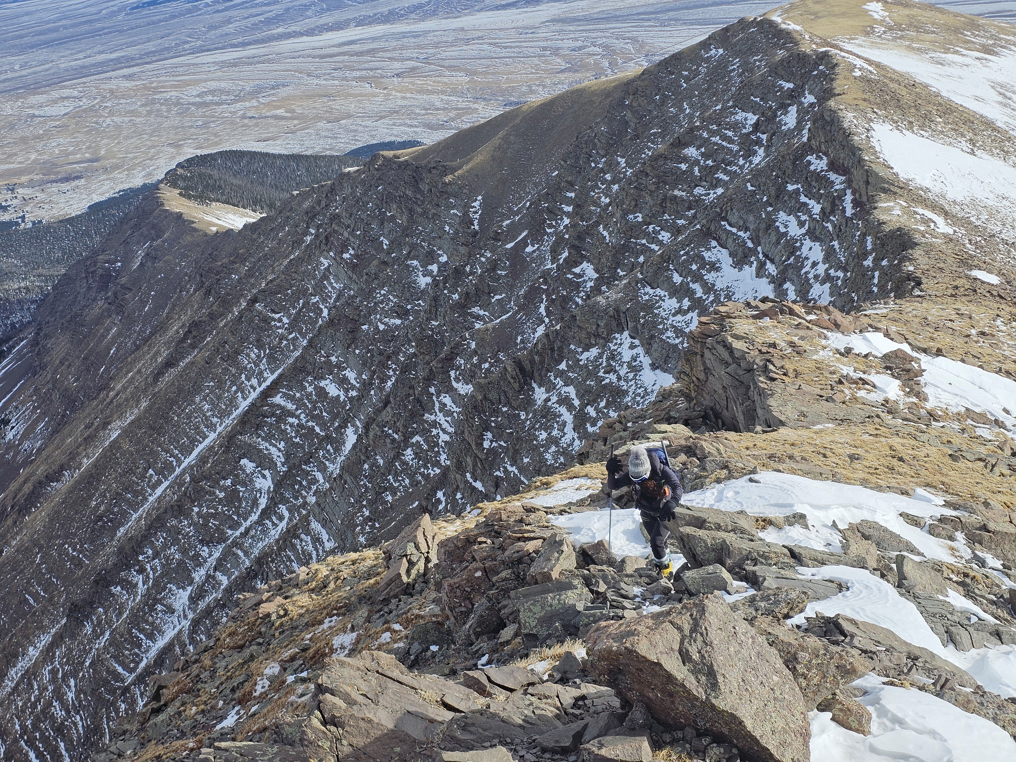 A trekker ascends Humboldt peak in a dry early witner with little snow on the ground.