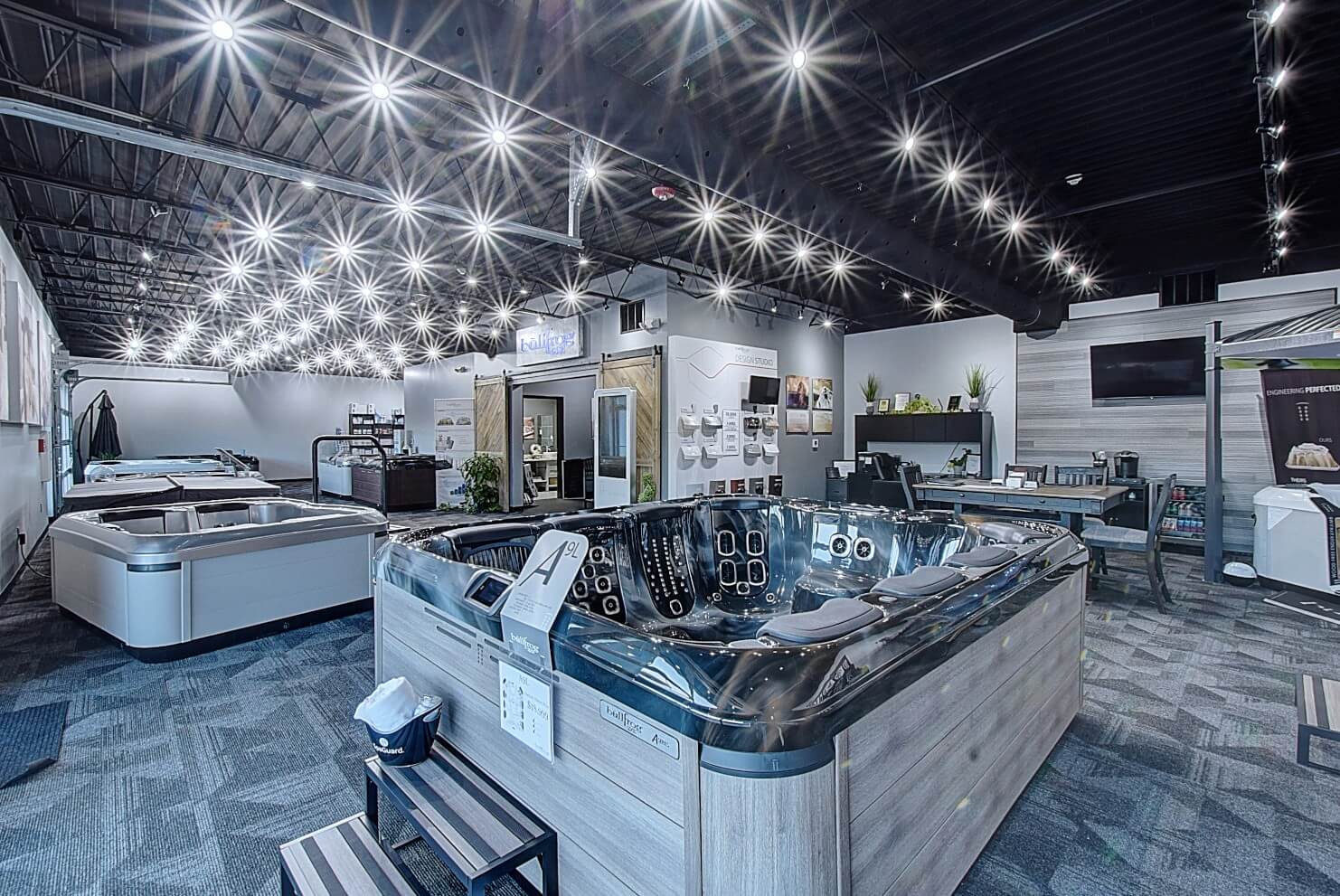 A spacious showroom filled with neatly arranged spas and hot tubs and bright overhead lights.
