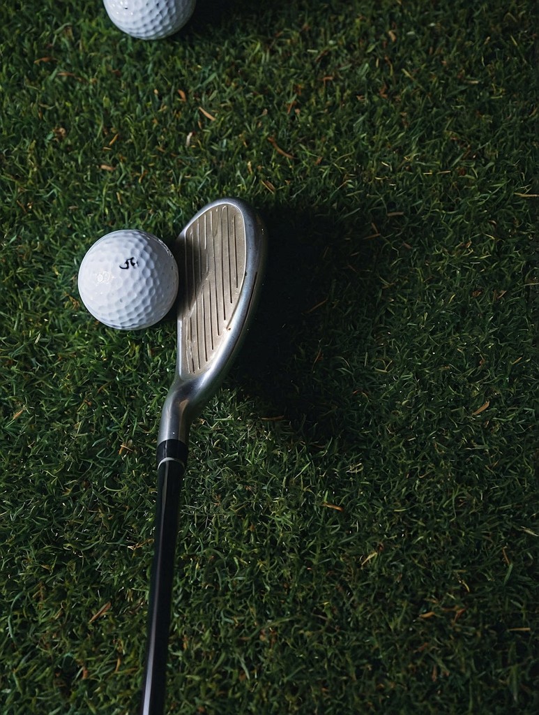 gold ball with golf club on the green grass