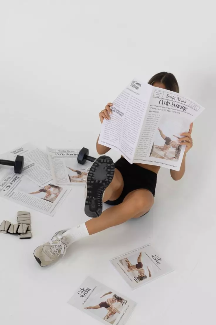 Person sitting on the floor reading, surrounded by small training weights