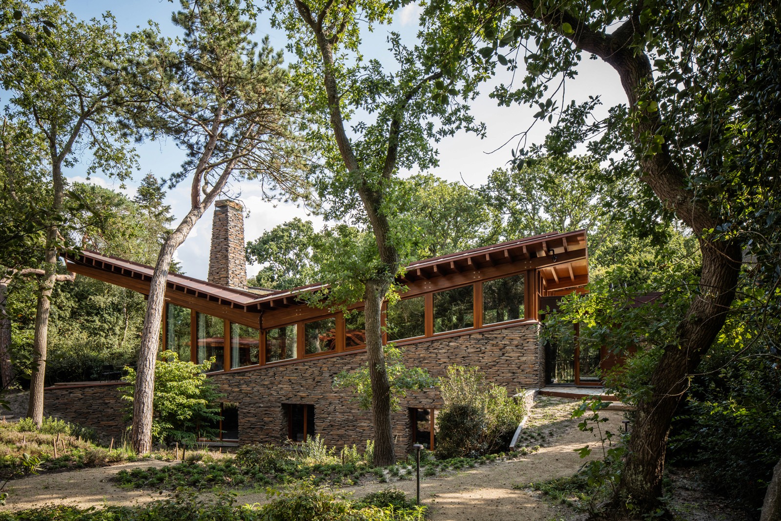 Huis met stenen buitenkant en houten details, gelegen in een bosrijke omgeving.