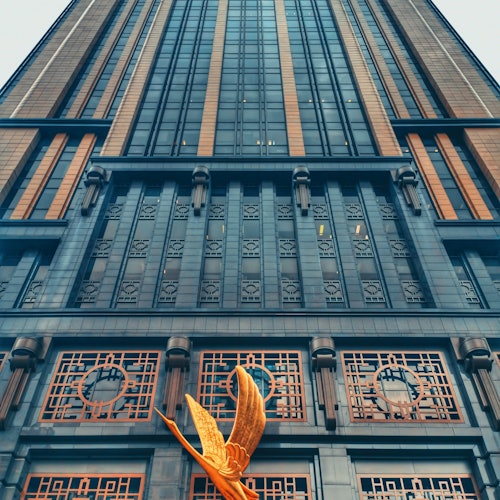 高楼有着精致的窗户和几何图案，入口处有一个金色的蝴蝶雕塑。