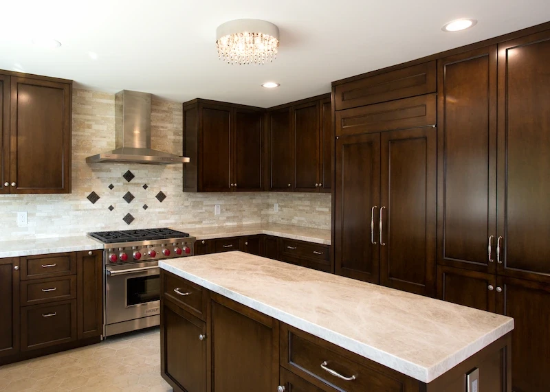 Modern kitchen with rich wood cabinetry, beige stone backsplash, and large central island in Orange Interior Remodel.