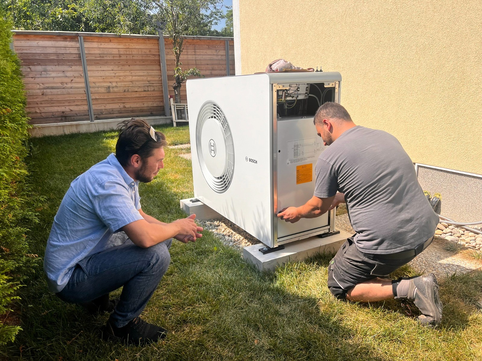 Techniker installieren eine Wärmepumpe in einem Garten