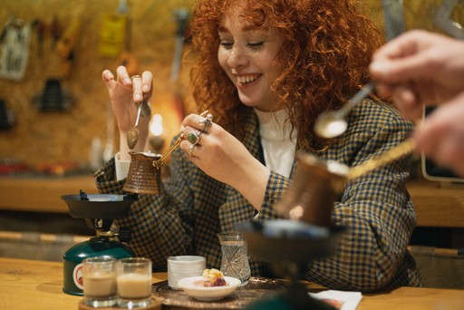 Smiling woman holding a traditional Turkish coffee pot while learning how to make Turkish coffee in a cultural class in Istanbul.