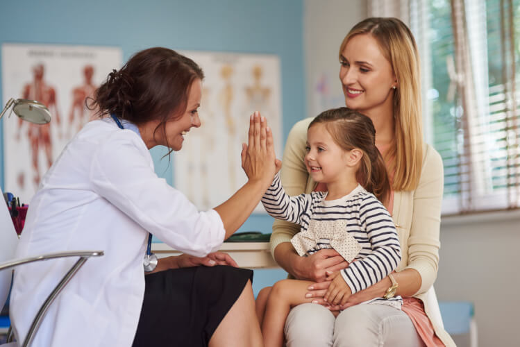 Medic și copil dându-și ‘high-five’ la consultație – siguranță medicală prin asigurarea de sănătate BIXMA.