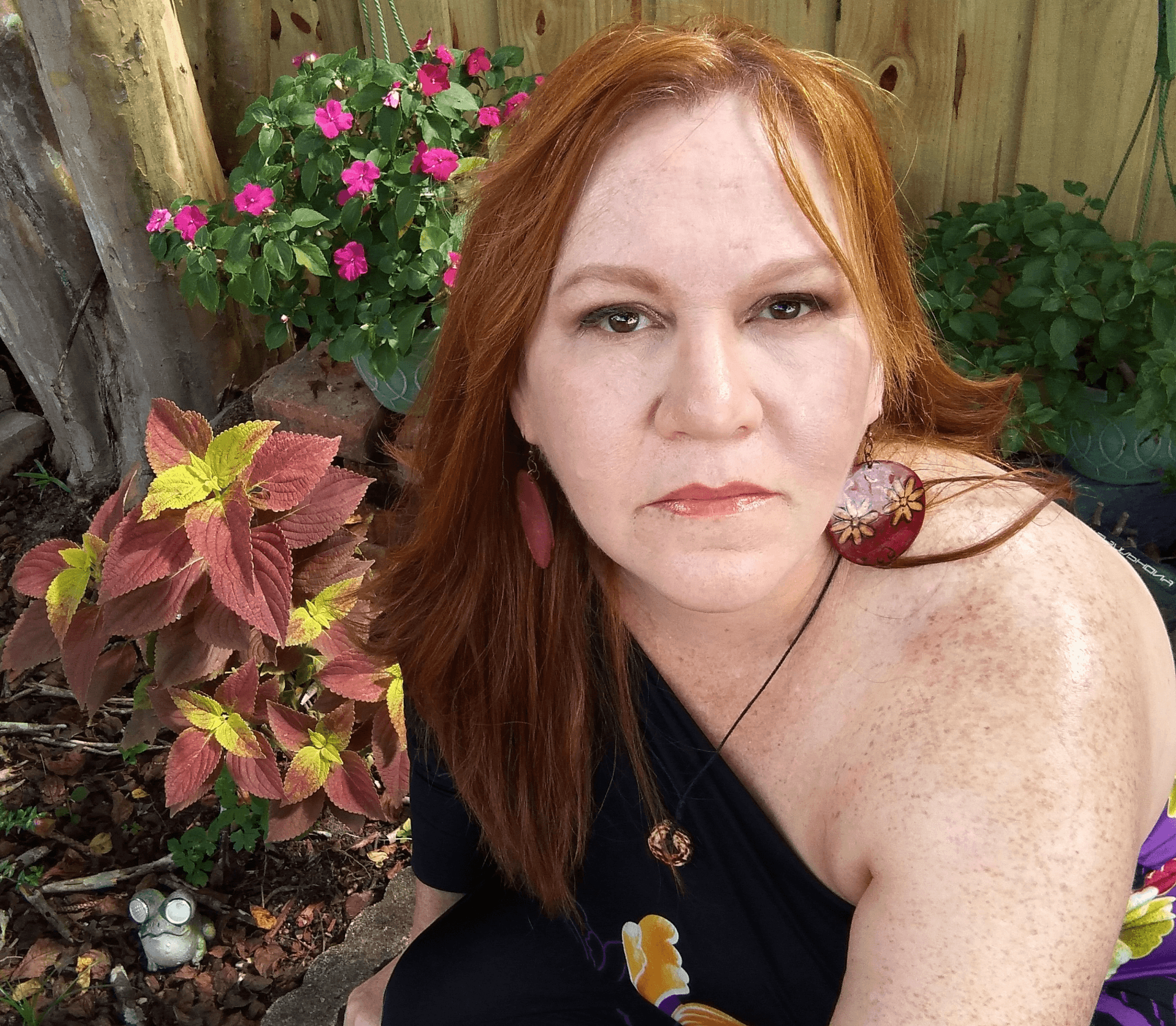 Ruth N Ribeiro seated in a garden with colorful flowers, reflecting the natural inspiration behind Monarch Enchanted.