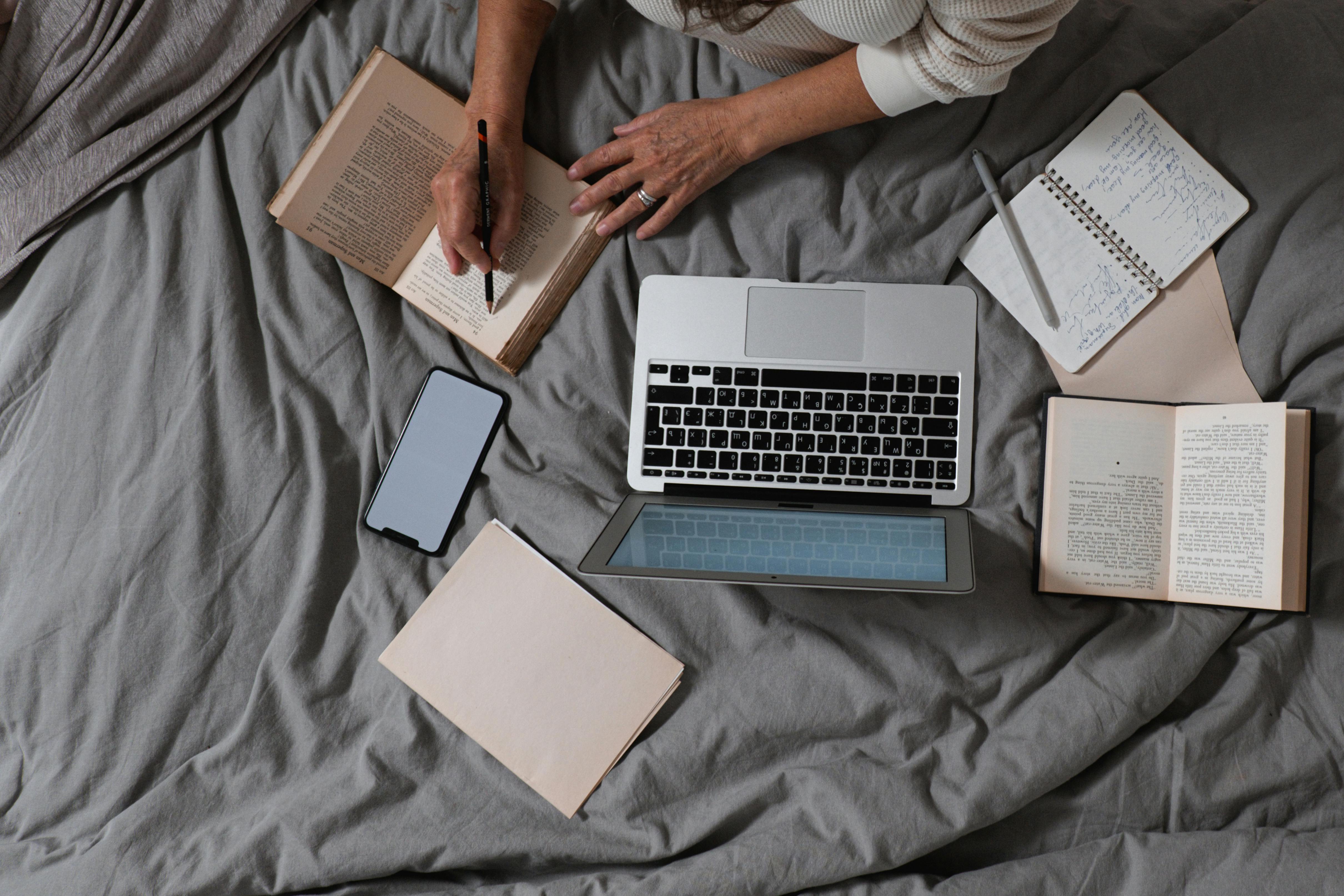Student studying with laptop, books, notebook, and smartphone showing AI tools in education blending traditional and digital learning methods