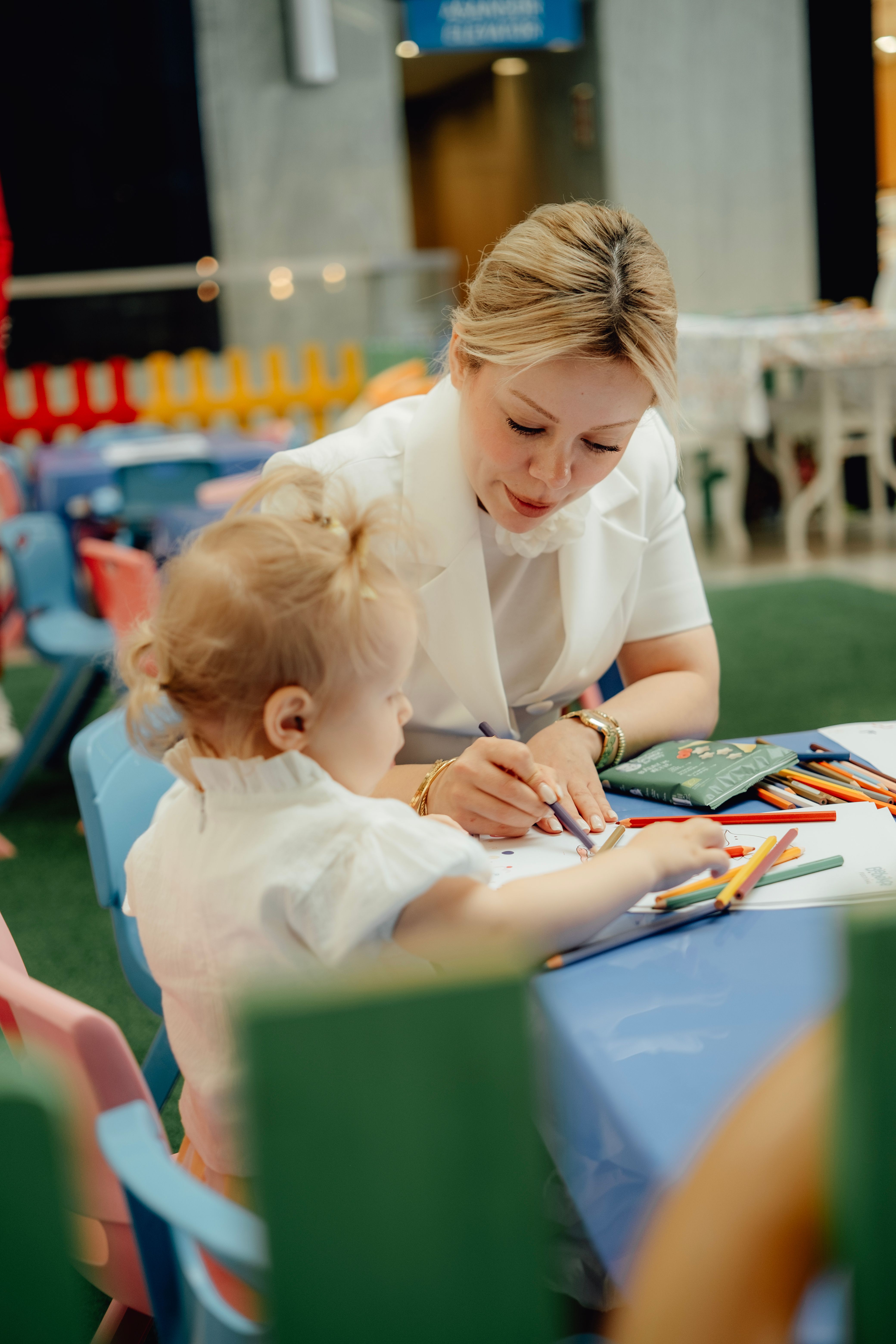 child sitting in front of table with white animal toy and containers of paints