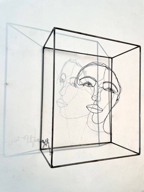 Sculpture en fil de fer représentant le visage d'une femme dans un cadre en fil de fer, vue détaillée de profil