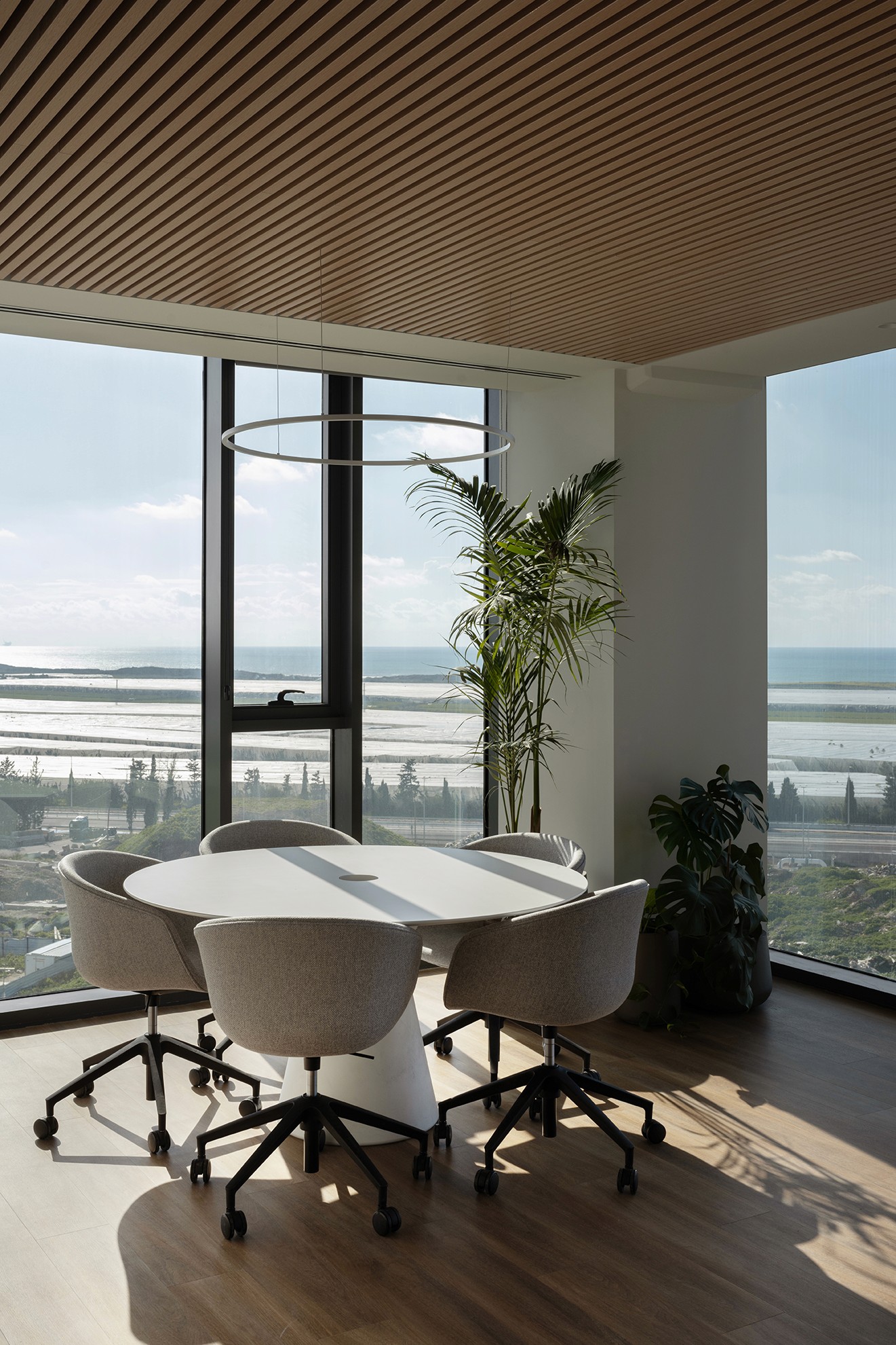פגישות מול הנוף: פינת ישיבה אקסקלוסיבית עם שולחן עגול וחלונות מסך (Curtain Wall) הצופים לנוף הפתוח ולים.