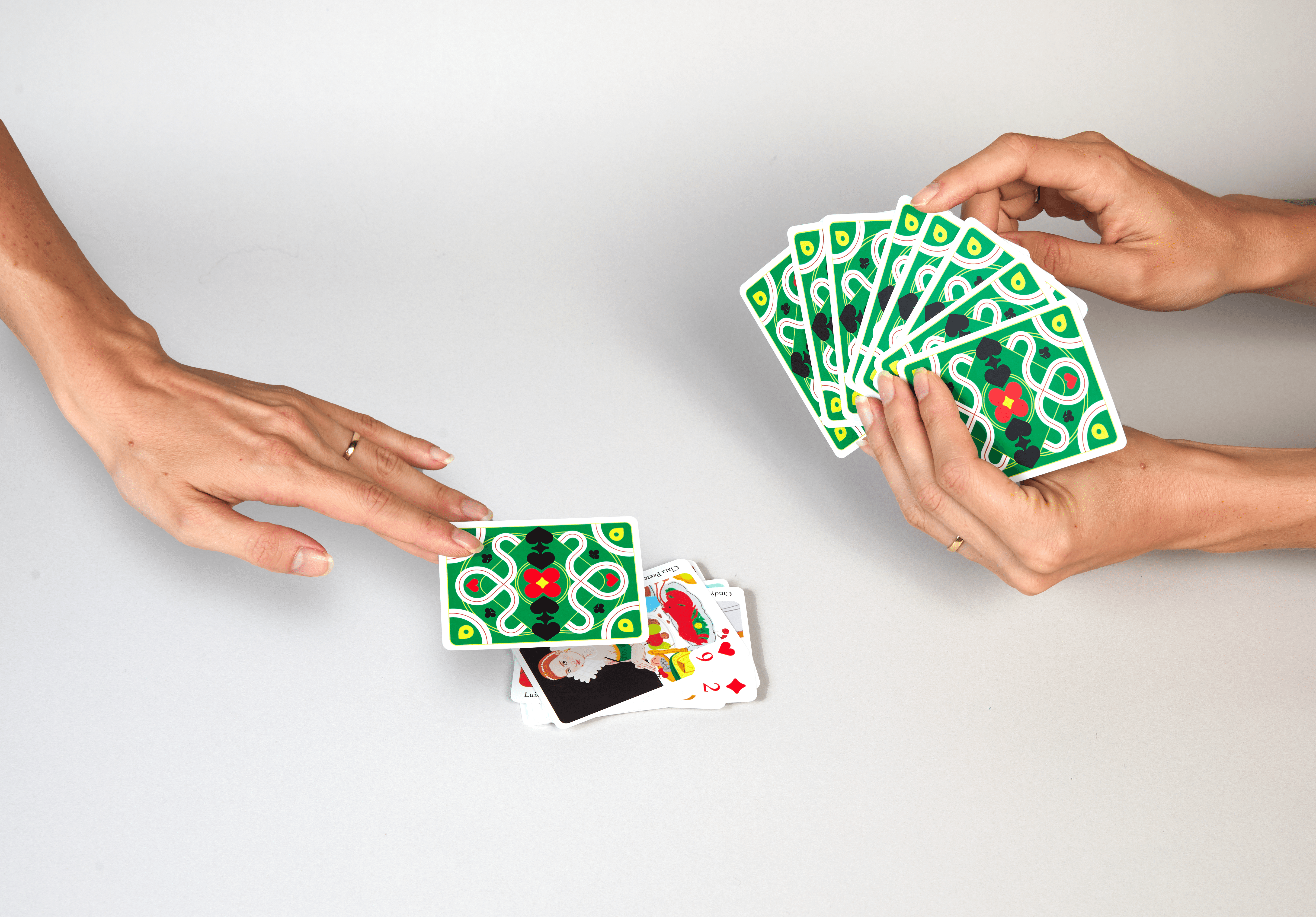Hands holding cards from the Queen of Arts deck, part of the colorful Gift Lab packaging series.