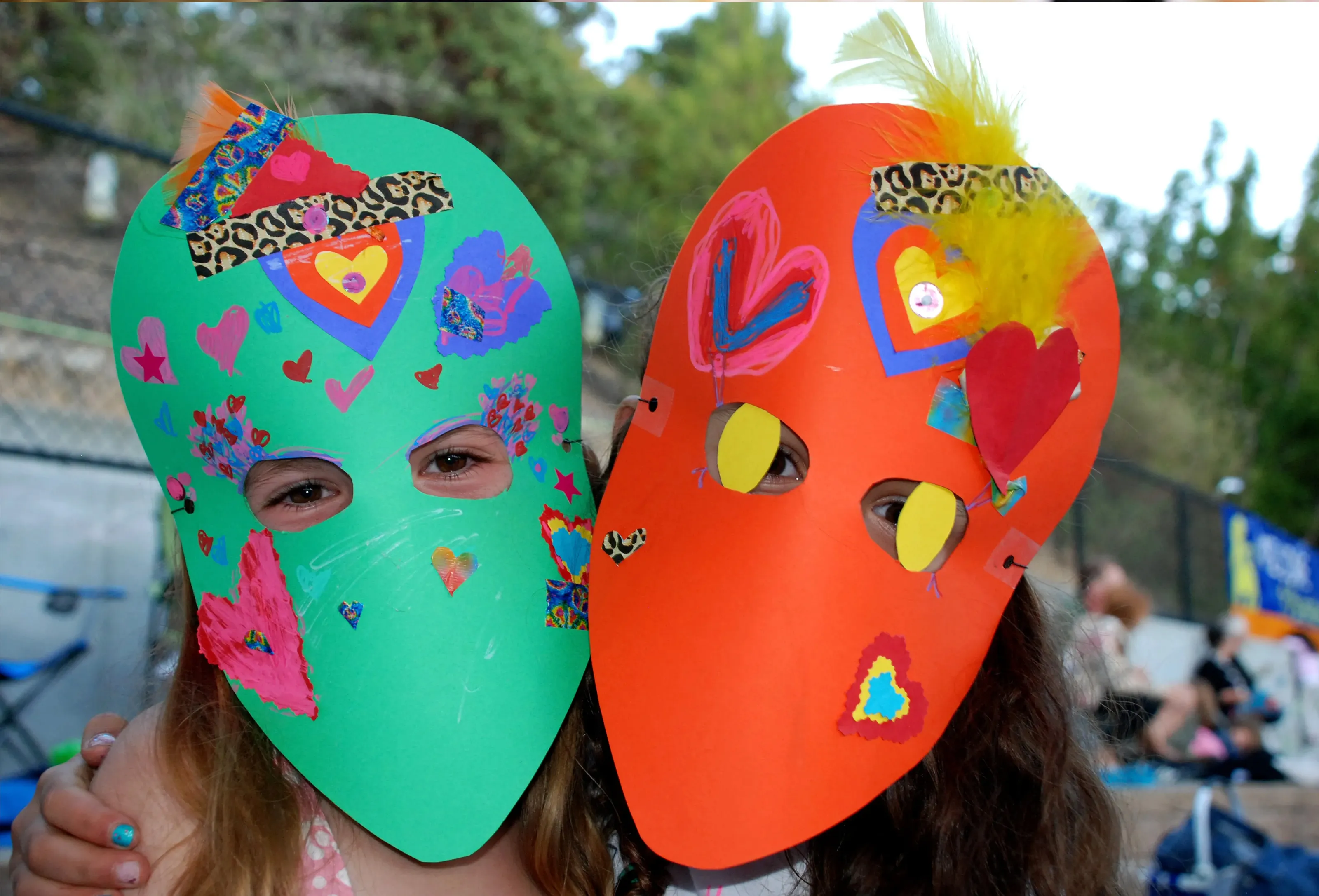 2 teens wearing  colorful cardboard mask