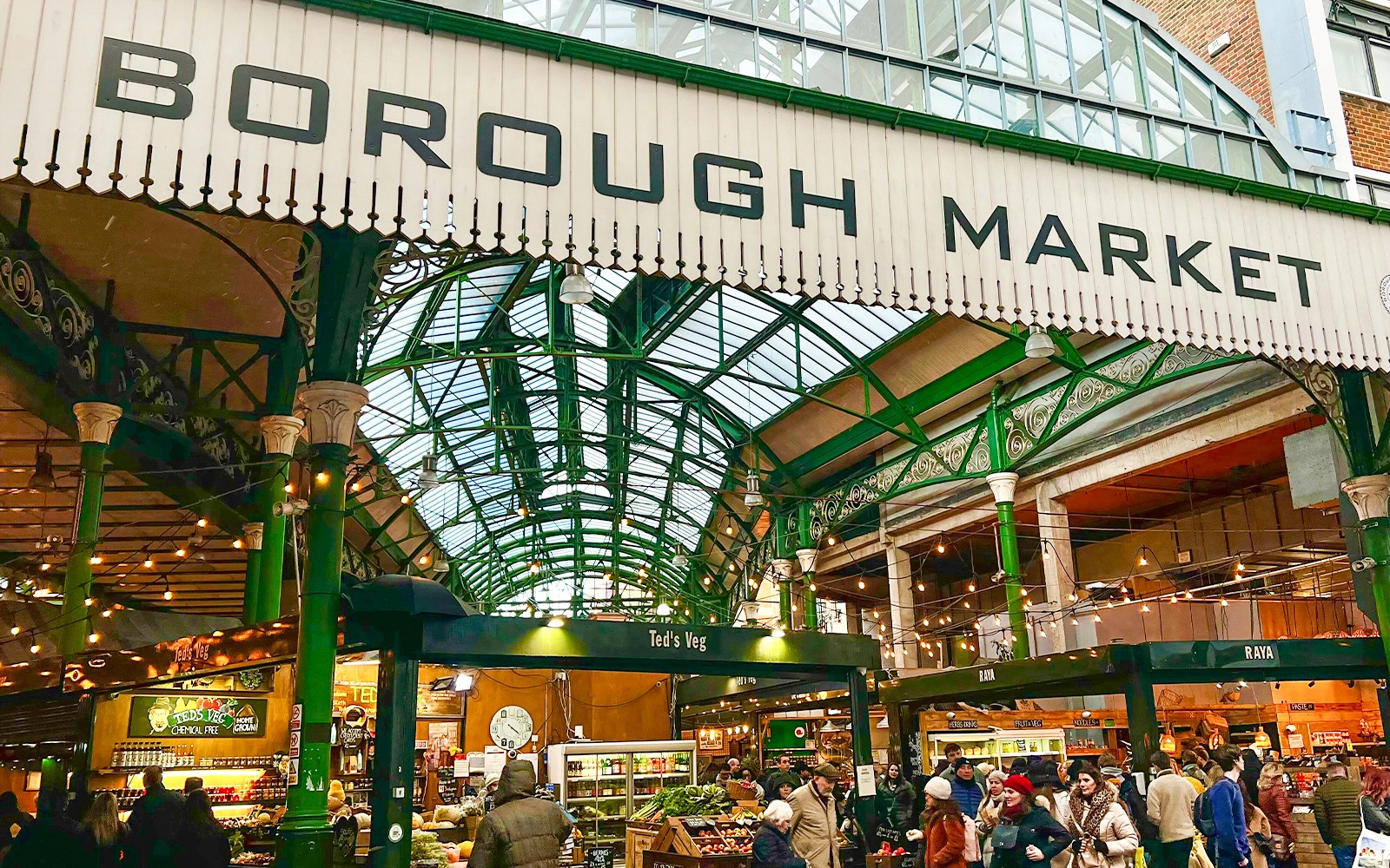Borough Market entrance with visitors exploring food stalls in London.