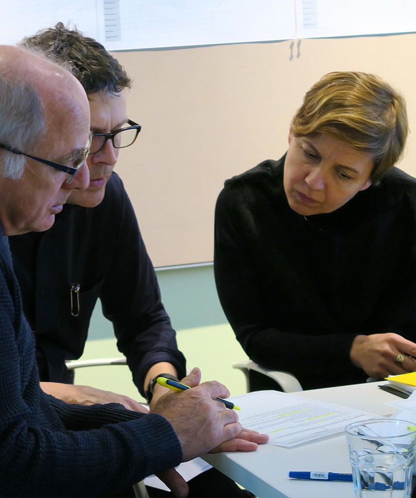 Three people seated, reviewing a document.