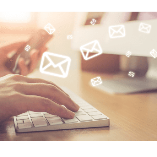 Hands typing on a keyboard with email icons floating over the desk.