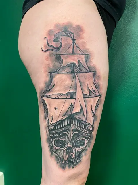 Svartvit tatuering med piratskepp och skalle på lår, High Heels Tattoo Västervik