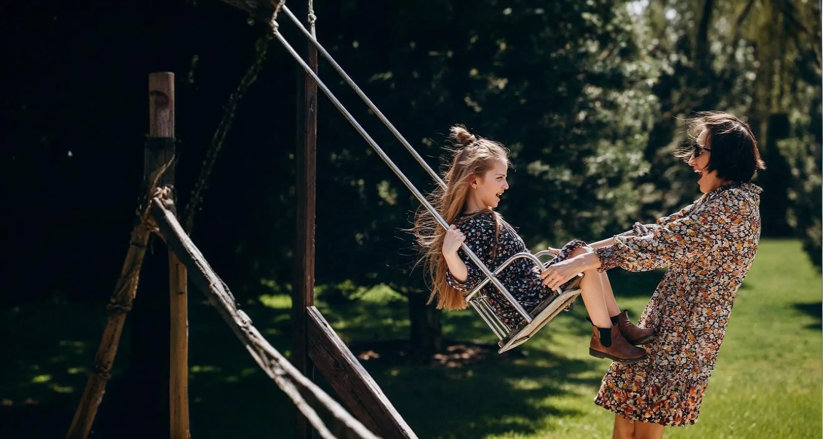 A mother joyfully pushes her daughter on a swing in a sunny backyard. The playful, carefree moment represents the stability and peace of mind that come from refinancing with Chris Lewis Home Loans.