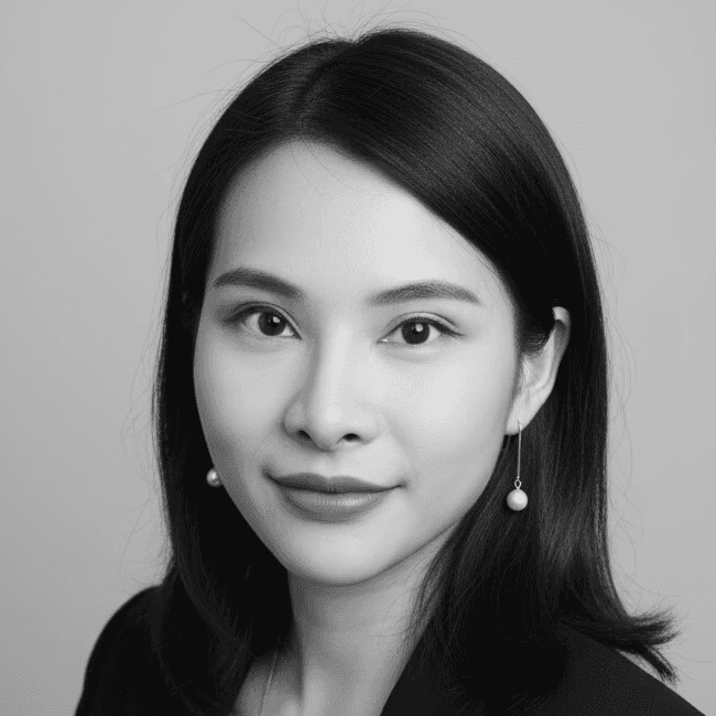 Portrait of a woman with long, smooth hair swept to the side, in a dark t-shirt, on a plain background.