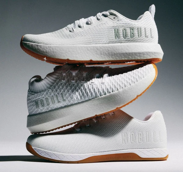 A hand pouring cherry vanilla flavoured soda from a colorful can in a tall glass, over a soft sky blue background, with two more cans on the side. Grape and Root Beer flavoured.