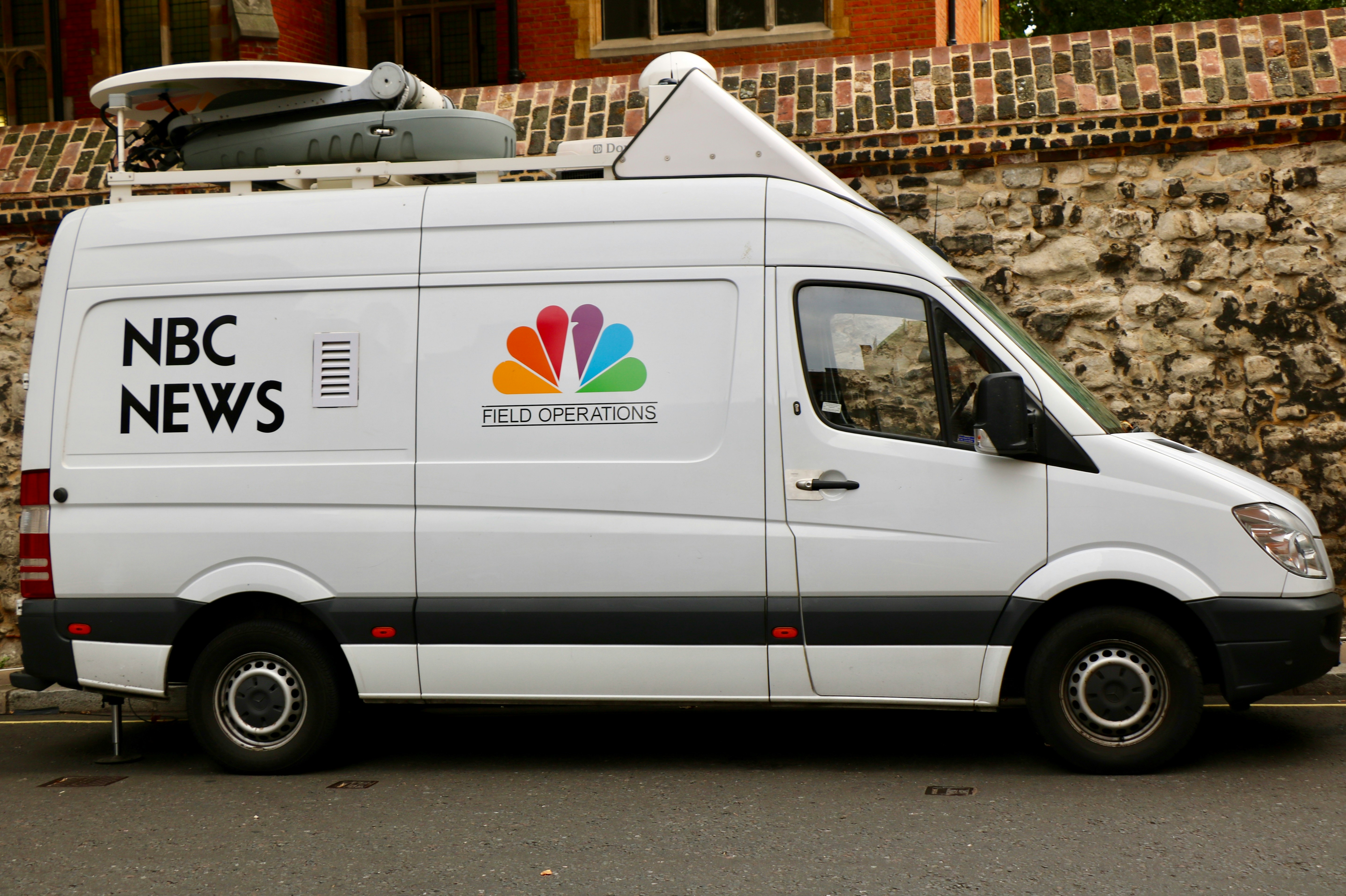 white NBC News van beside sidewalk