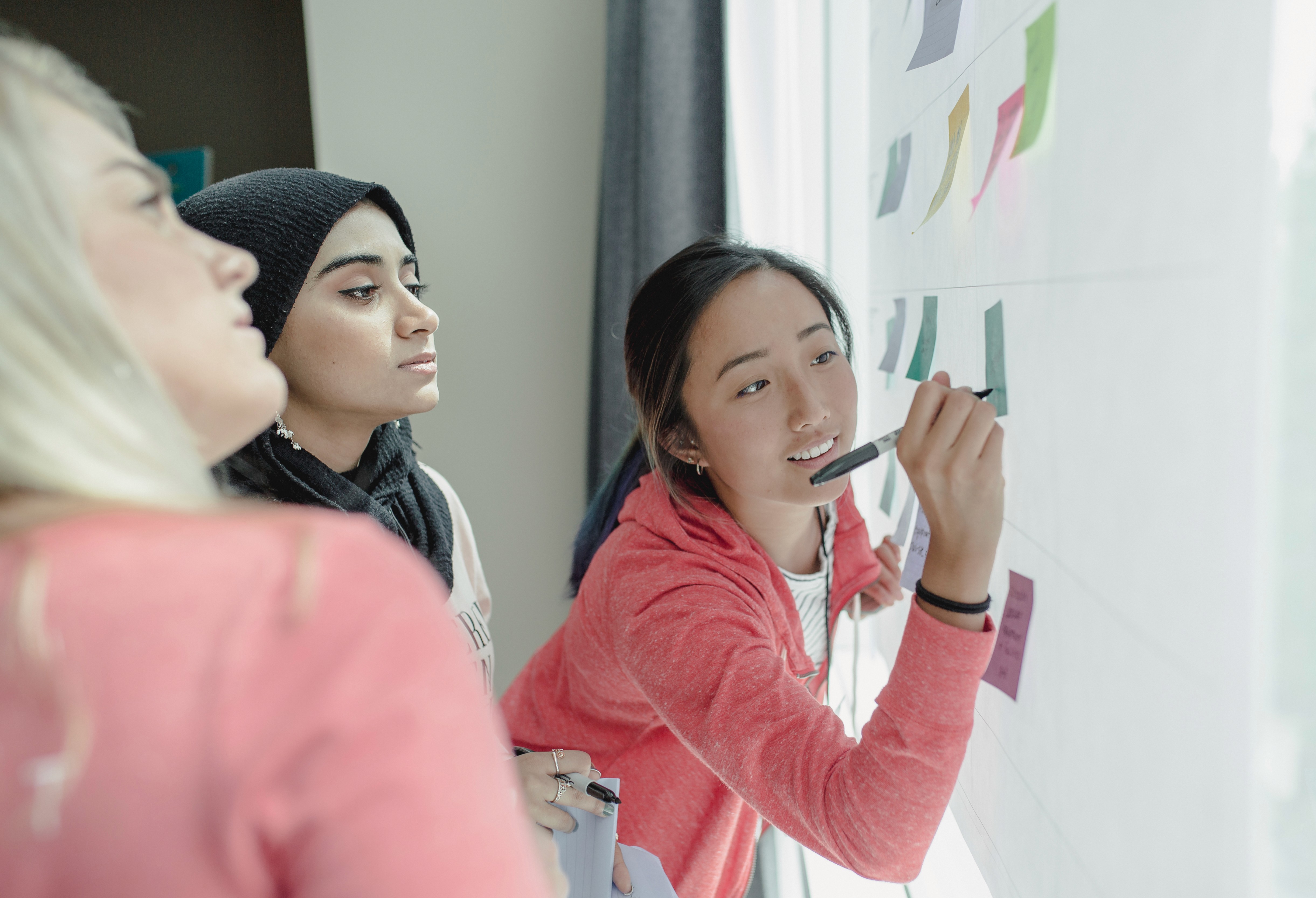 Three women writing on sticky notes during a workshop