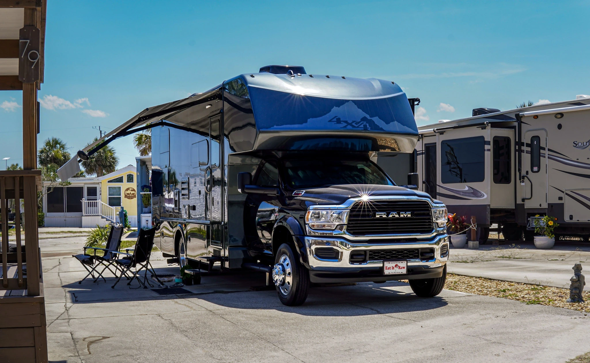 A black RAM truck towing a large modern fifth-wheel camper at a professional RV resort.