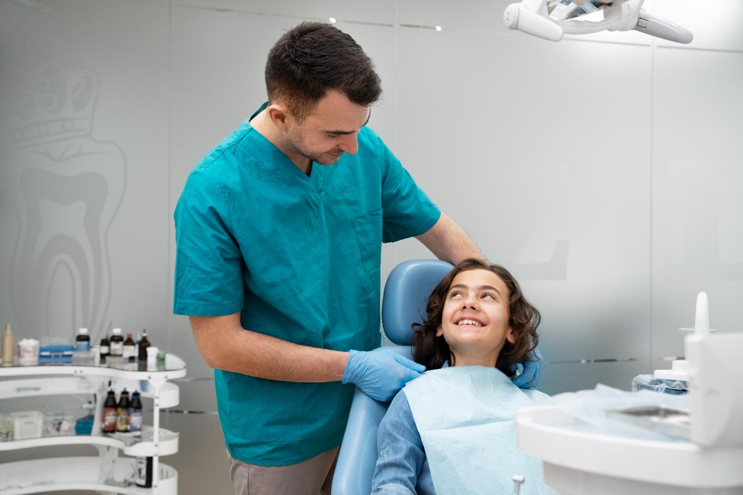 A young girl sitting in a dental chair, receiving dental treatment from a dentist and dental assistant.