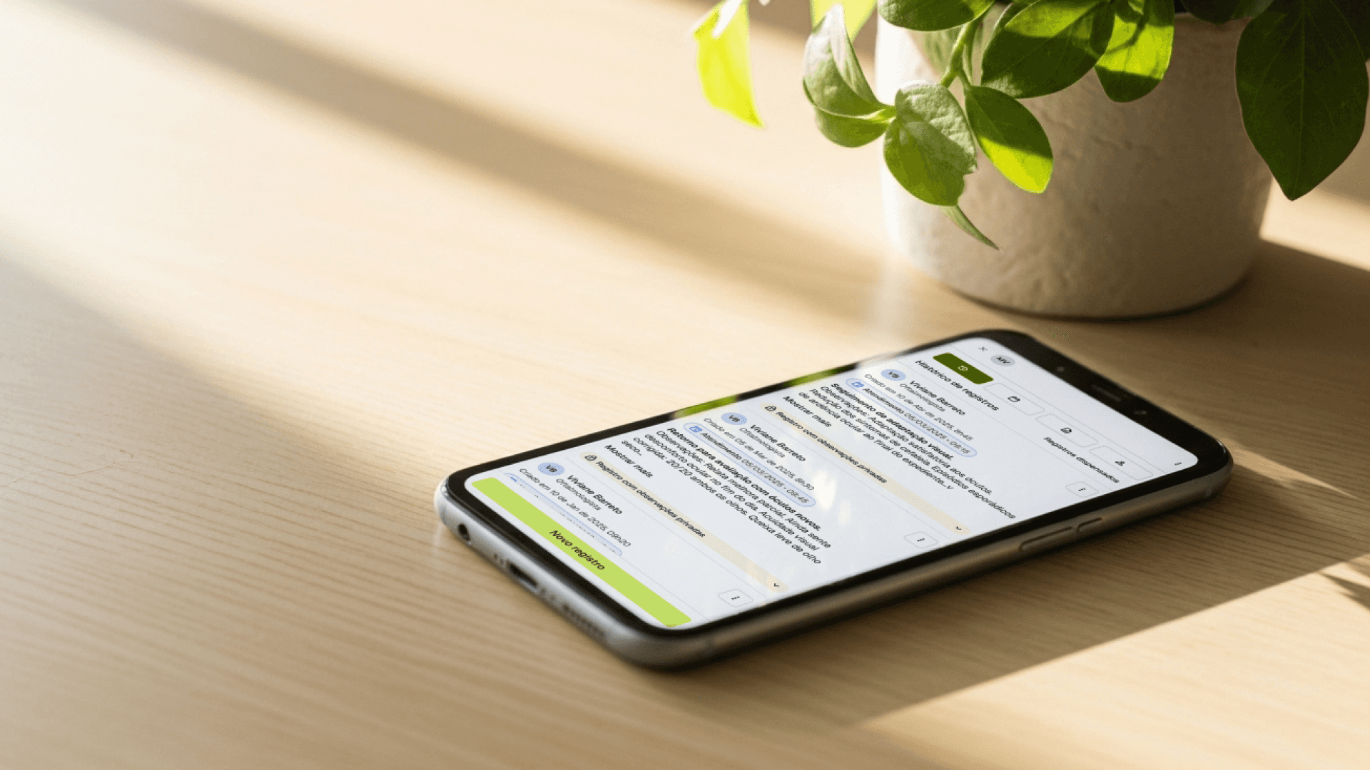 Celular apoiado sobre uma mesa de madeira, exibindo uma tela com interface de agenda inteligente da Tivita, em uma clínica com luz natural.